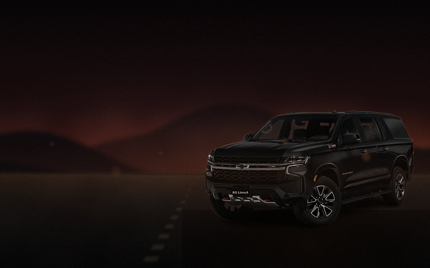 Black Chevrolet Suburban on a desert road to Indio as the sky burns out behind the mountains